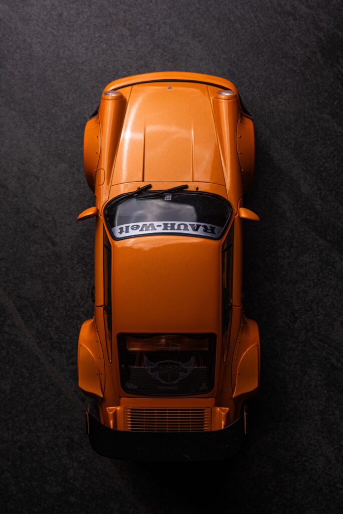 Stylish top view of a classic orange toy car on a dark textured surface, ideal for automotive themes.